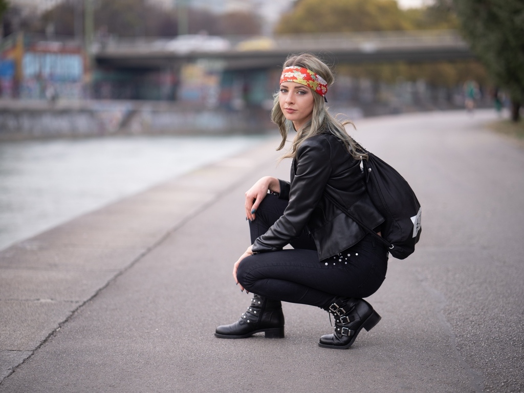 Девушка в черном костюме сидит на корточках