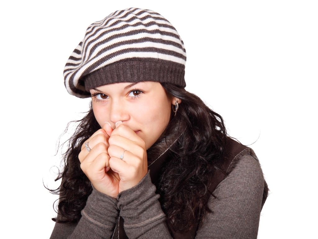 Девушка в теплой полосатой шапке на белом фоне