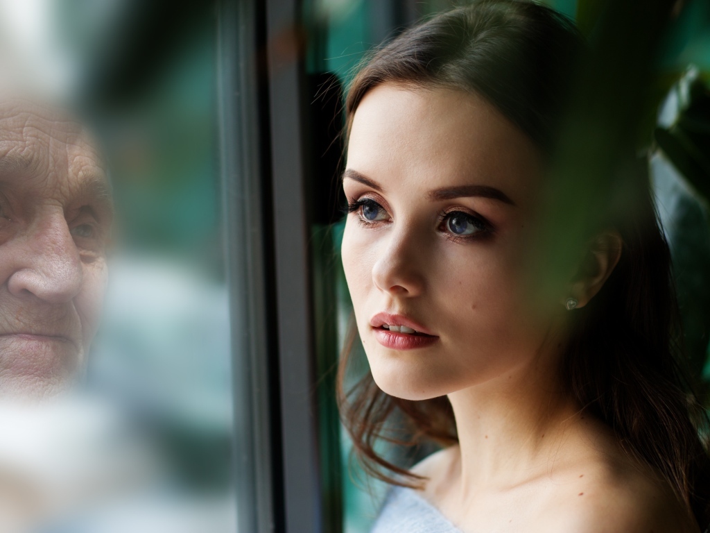 Девушка смотрит на свое отражение в старости