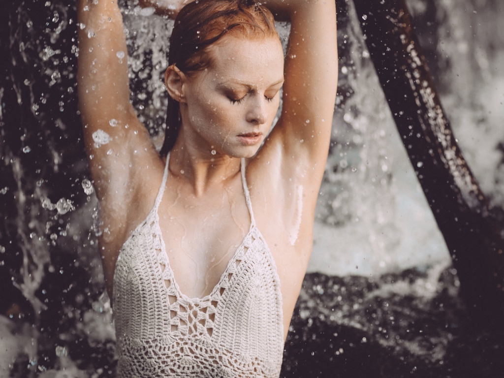 Рыжеволосая девушка в брызгах воды