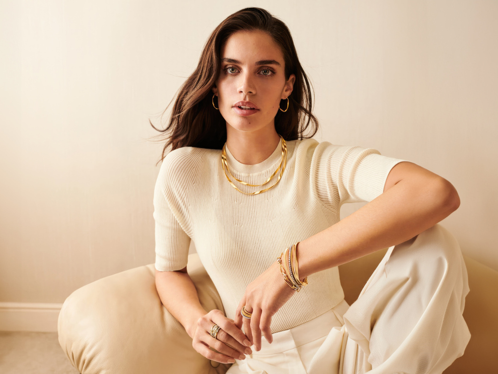 Модель Сара Сампайо в белом наряде сидит в кресле