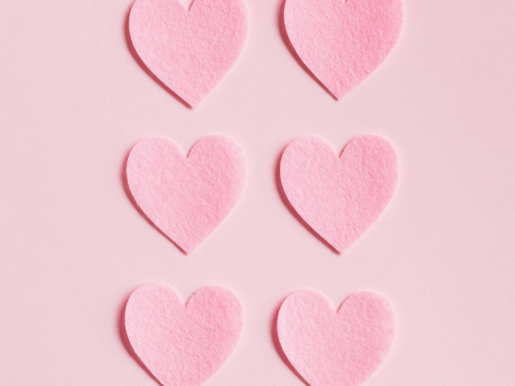 Маленькие бумажные сердечки на розовом фоне