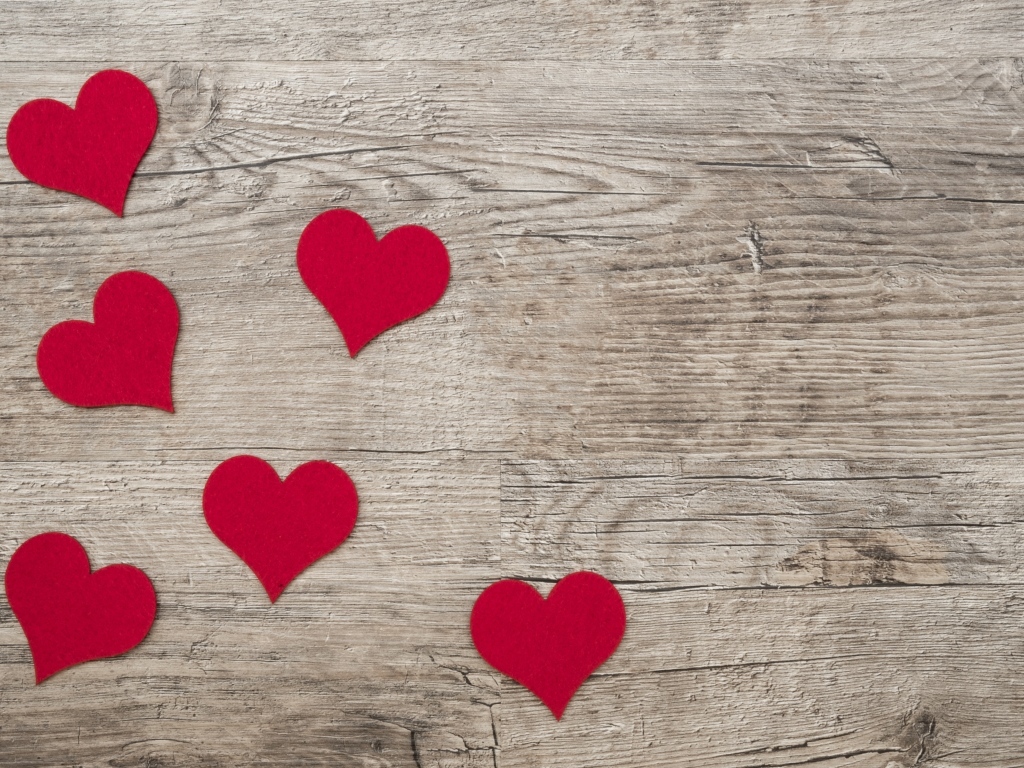 Маленькие красные сердечки на деревянном фоне