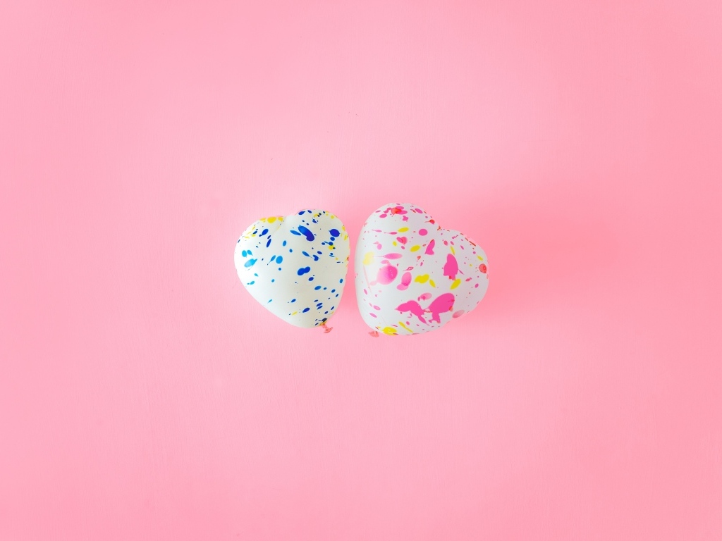 Два шарика в форме сердца на розовом фоне