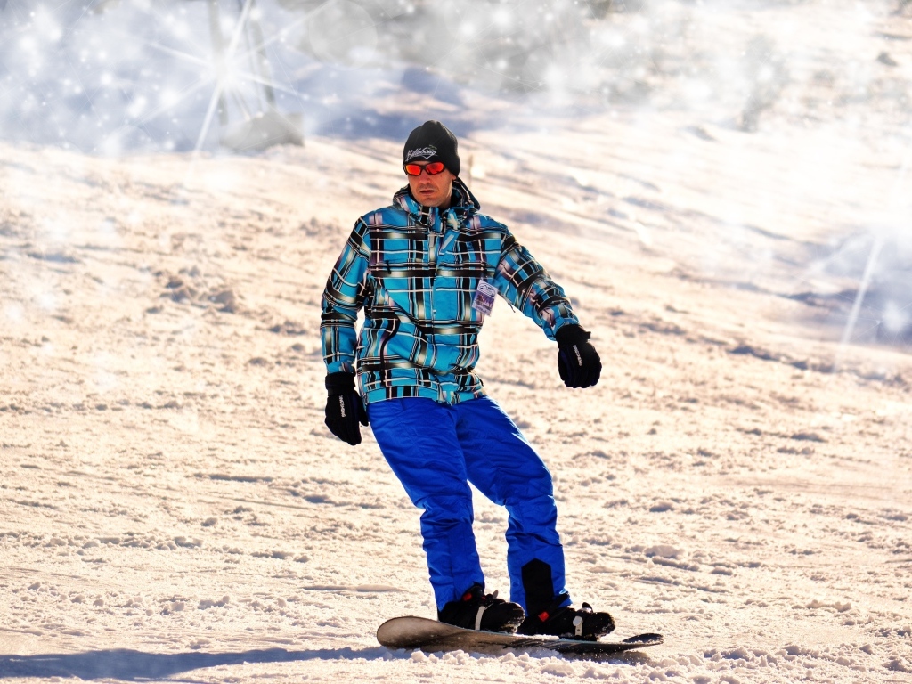 Мужчина сноубордист спускается по склону