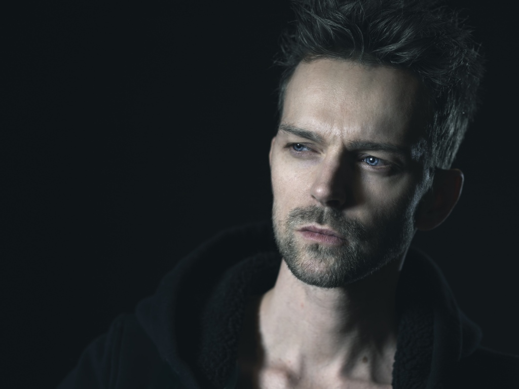 Серьезный голубоглазый мужчина на черном фоне