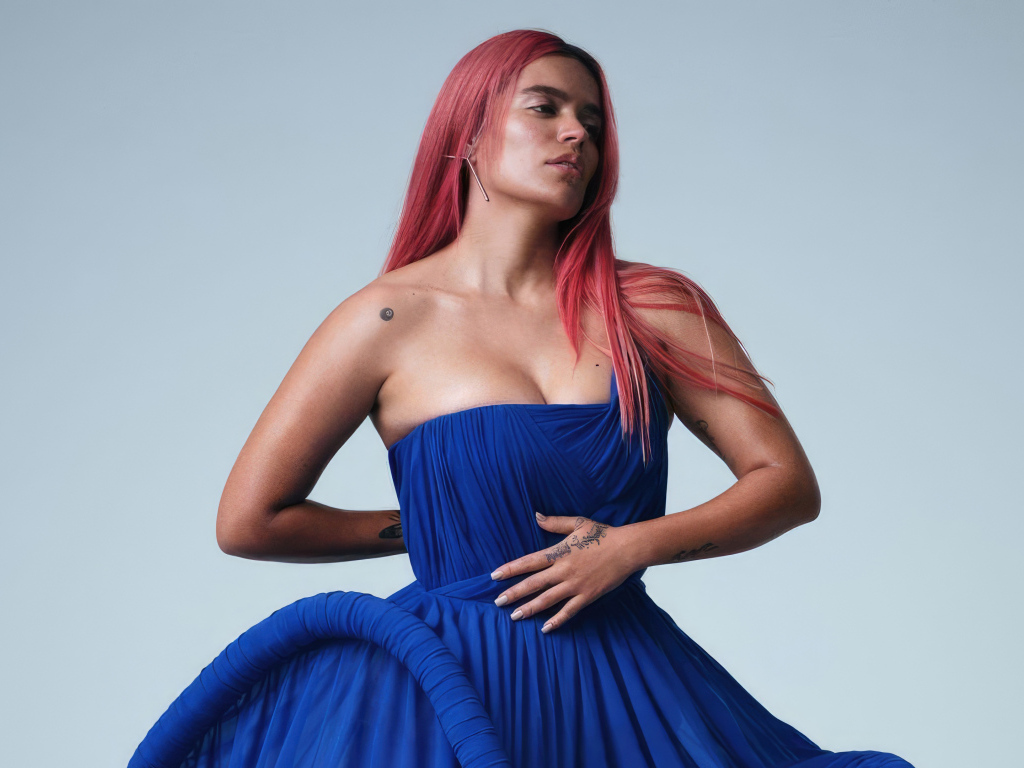 Певица Karol G в синем платье на сером фоне