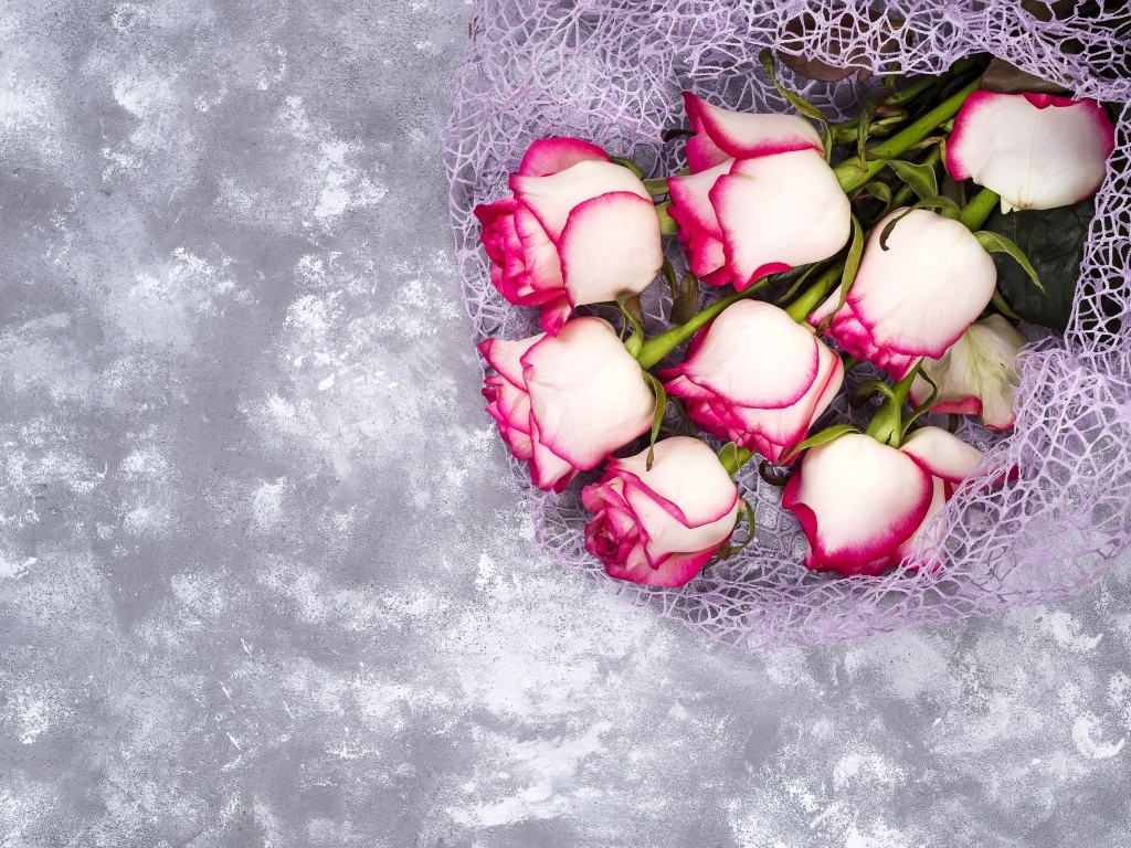 Красивый букет роз в упаковке на сером столе