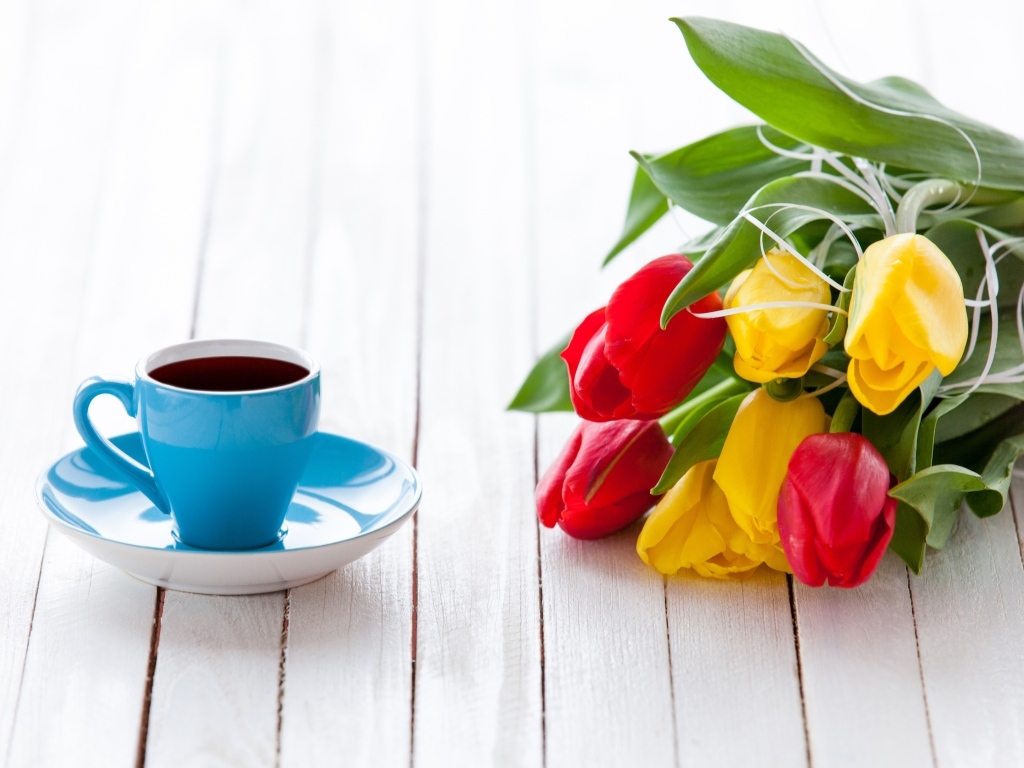 Голубая чашка на столе с букетом тюльпанов