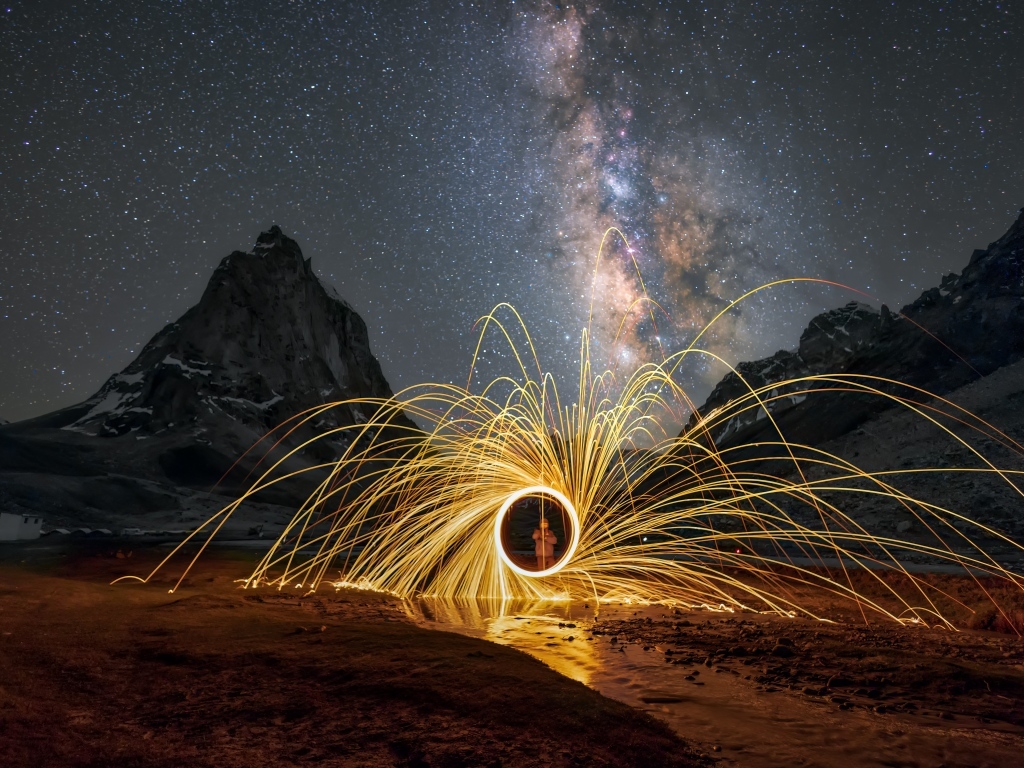 Огненное шоу под ночным красивым небом в горах