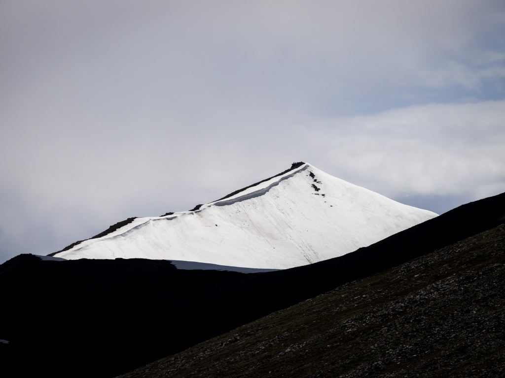 Заснеженная вершина горы под грозовым небом