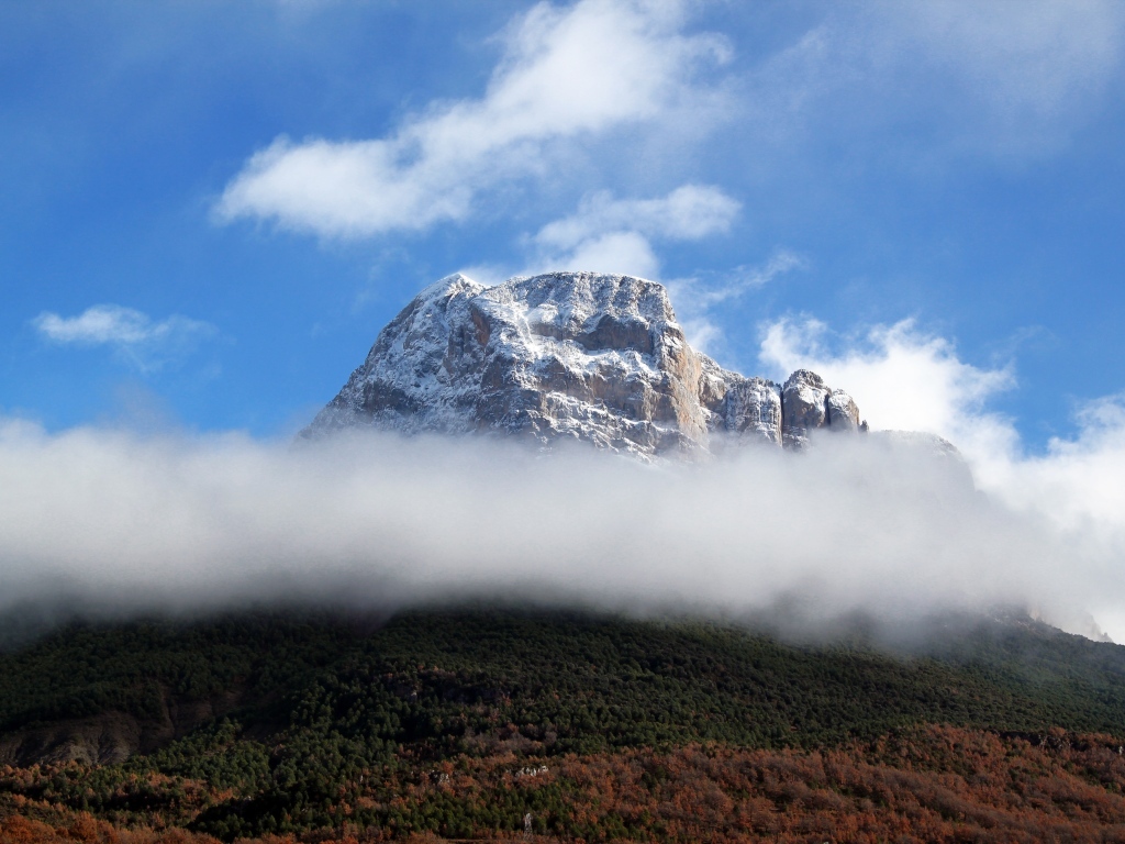 Заснеженная горная вершина в белых облаках