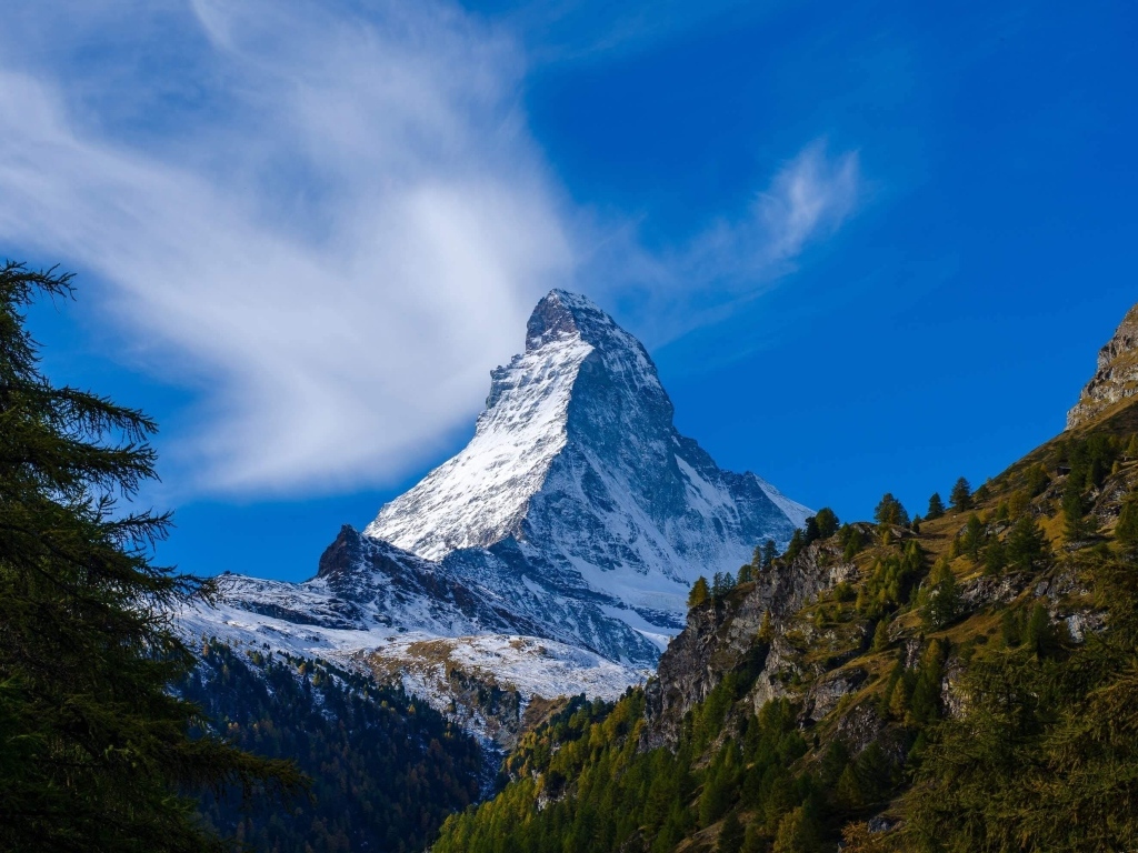 Вид на высокую заснеженную гору под голубым небом