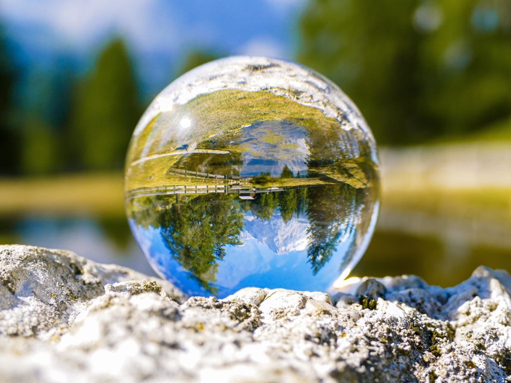 Стеклянный шар стоит на камне у воды