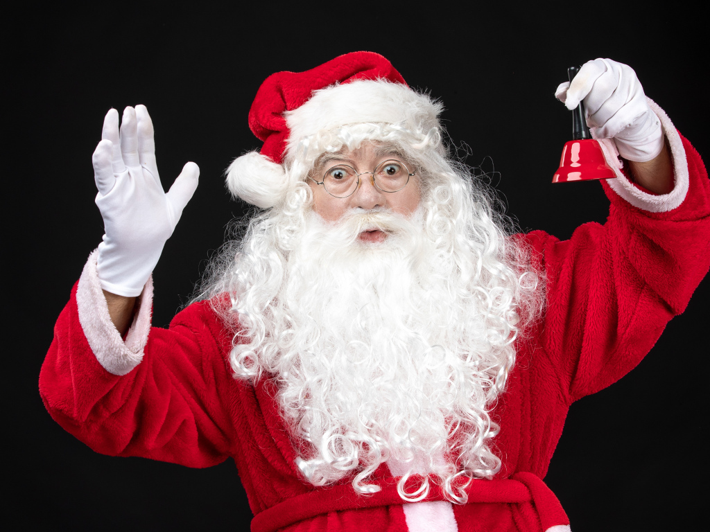 Удивленный Санта Клаус с колокольчиком в руках