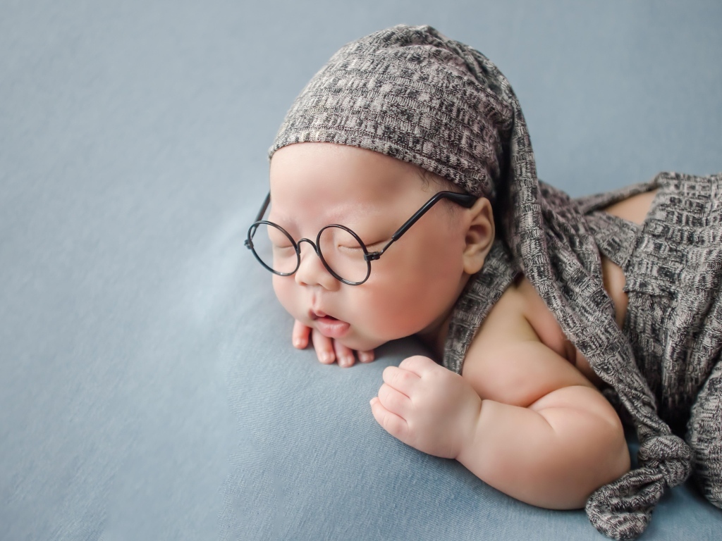 Забавный малыш в очках одет в серый костюм