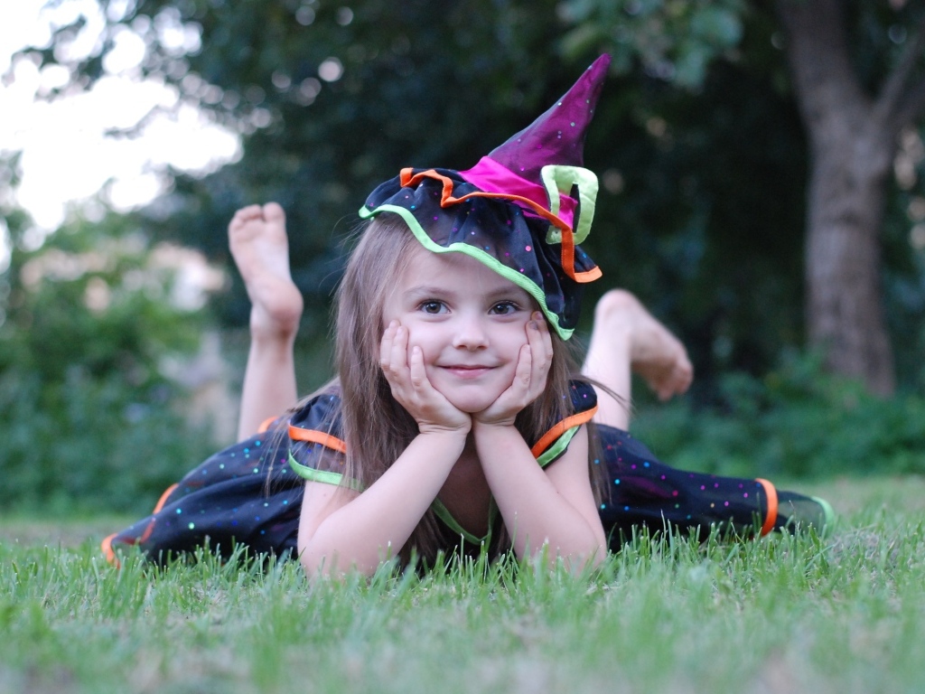 Девочка в костюме лежит на зеленой траве