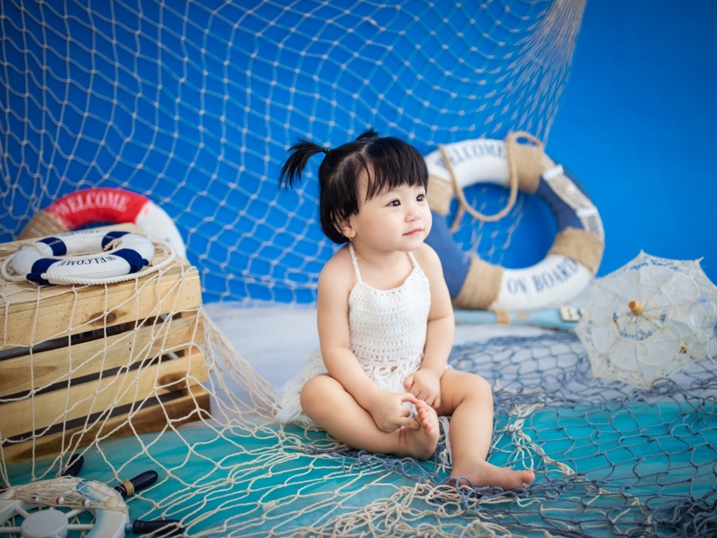 Маленькая девочка азиатка со  спасательным кругом и сетью 