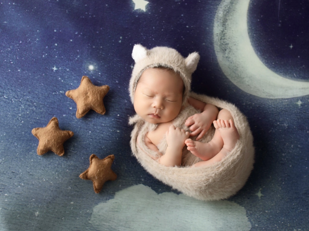 Маленький спящий грудной ребенок на синем покрывале