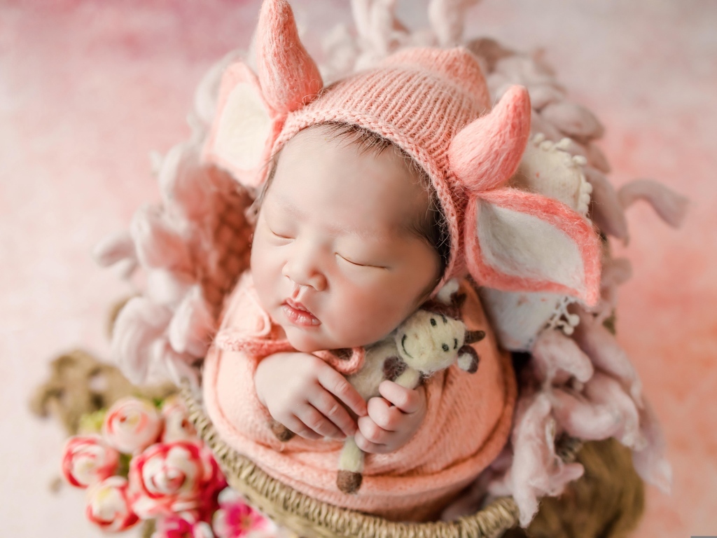 Маленький спящий новорожденный ребенок в шапке с рогами