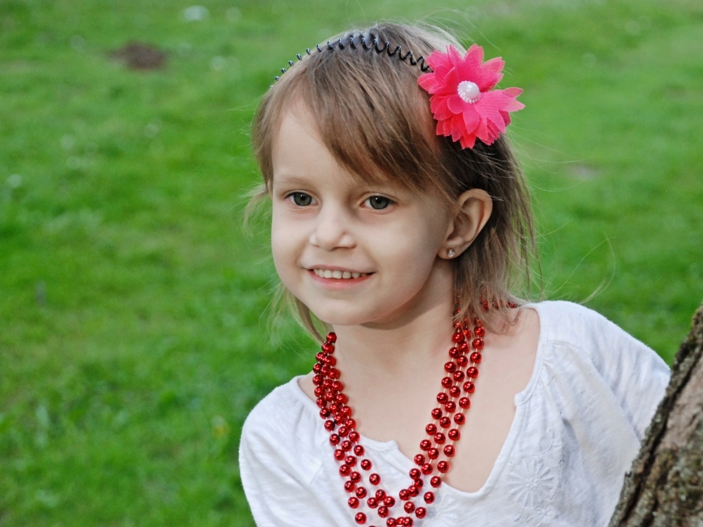 Улыбающаяся девочка стоит у дерева