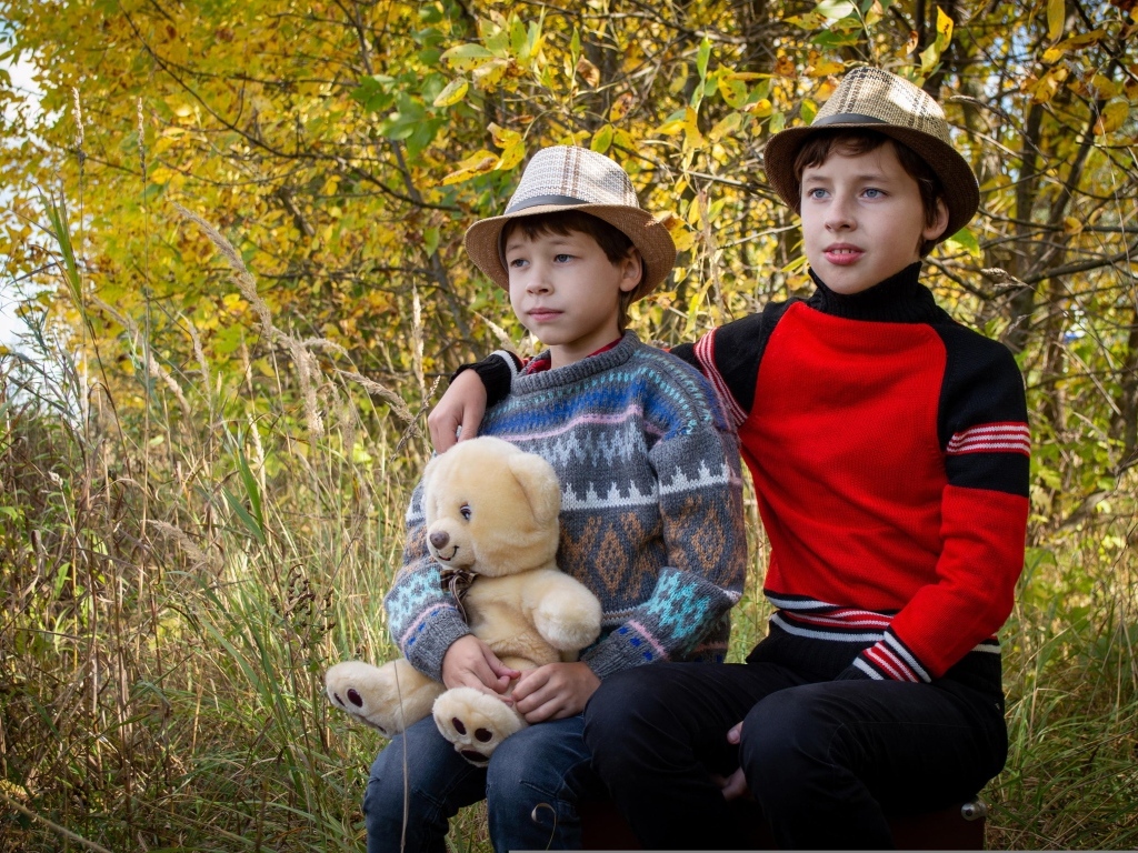 Два мальчика с игрушкой сидят у дерева