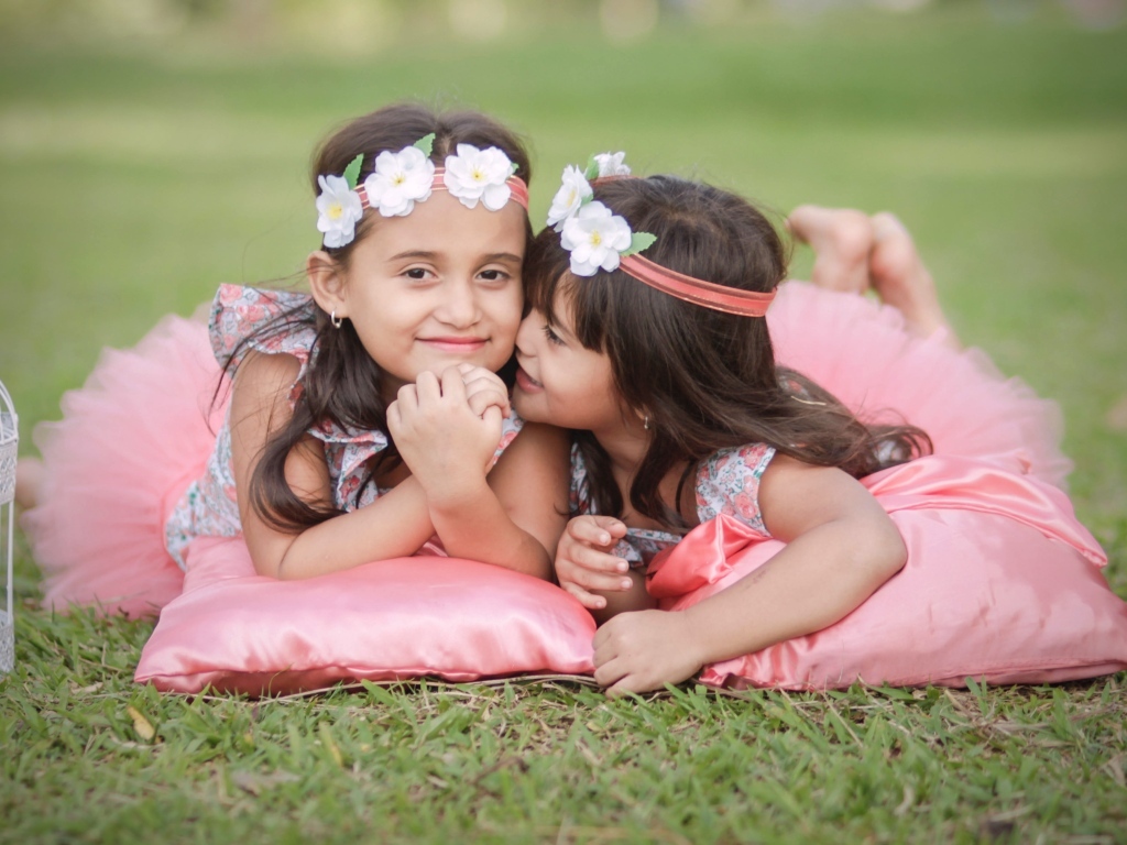 Две маленькие девочки лежат на подушках на траве