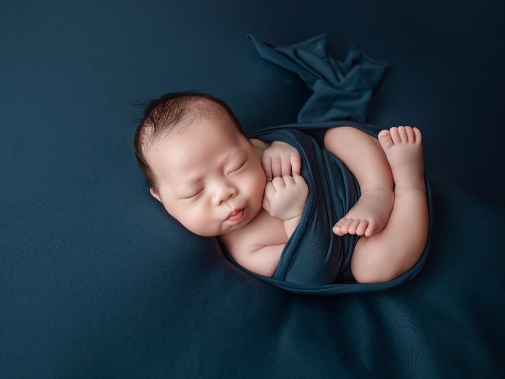 Новорожденный малыш в черном покрывале