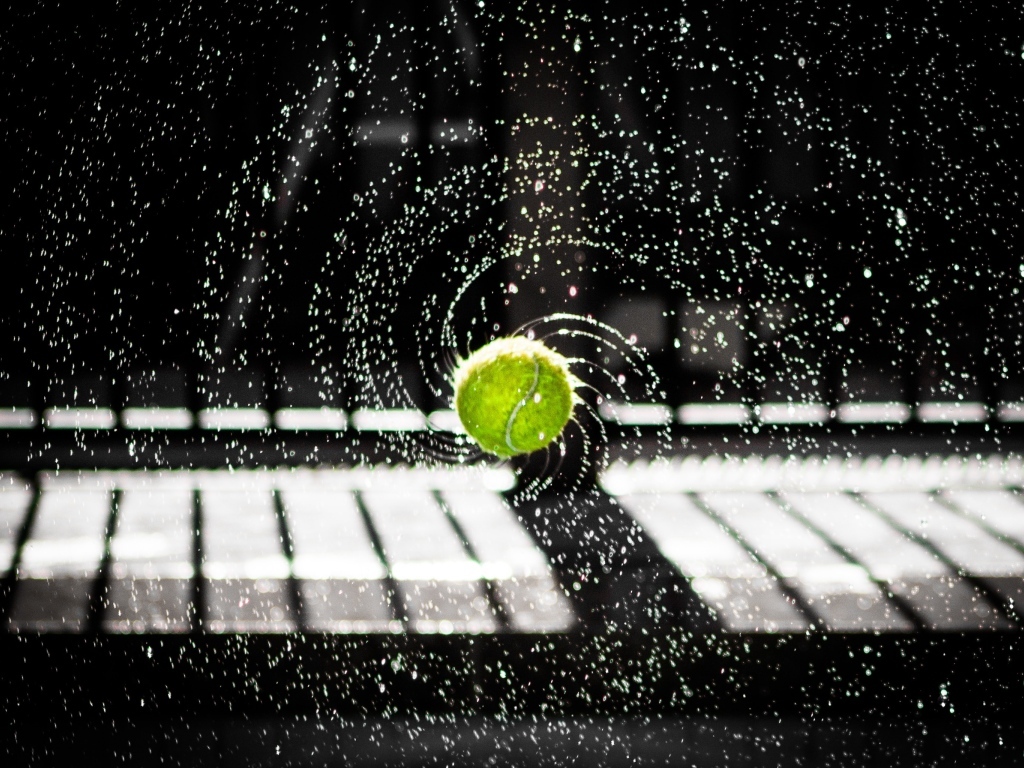 Теннисный мяч в брызгах воды