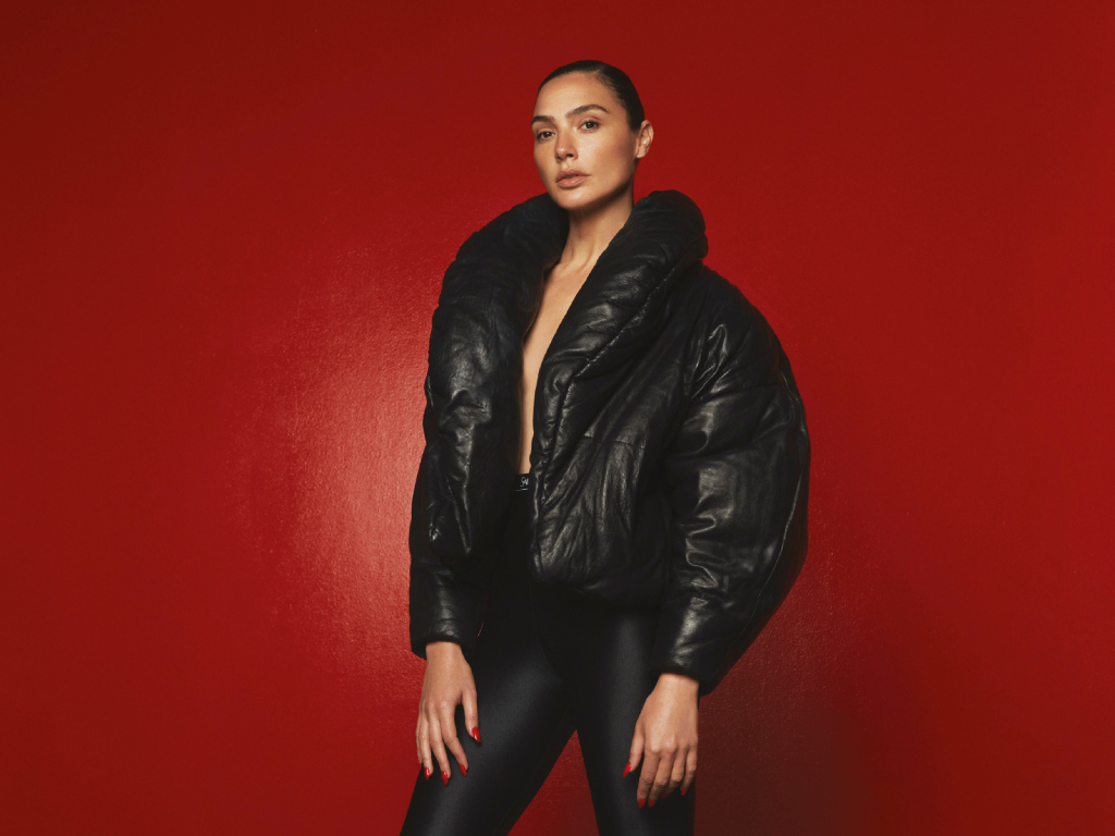 Актриса Галь Гадот в черной куртке на красном фоне