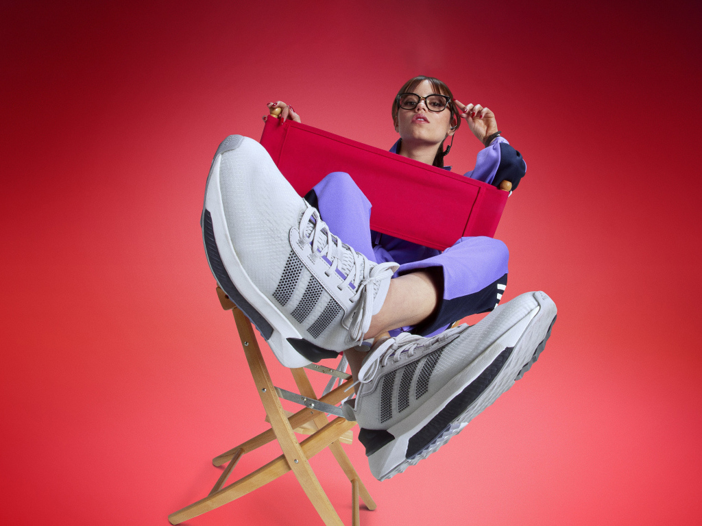 Актриса Дженна Ортега в кроссовках адидас сидит на стуле