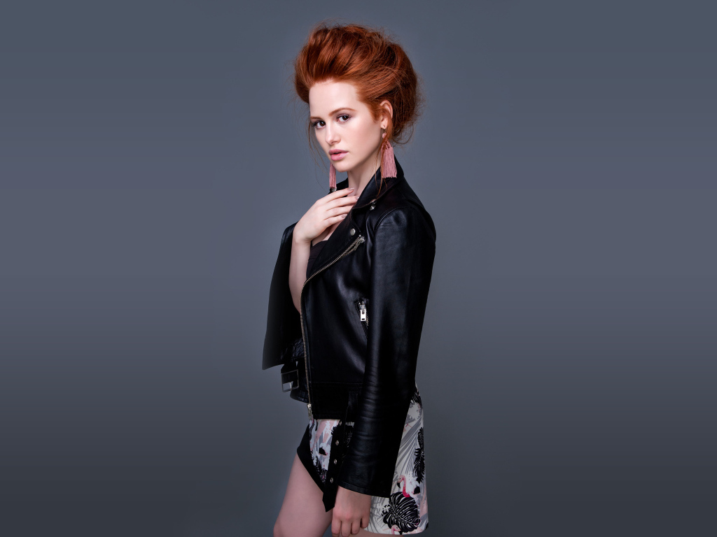 Рыжеволосая актриса Мэделин Петш в черной куртке на сером фоне