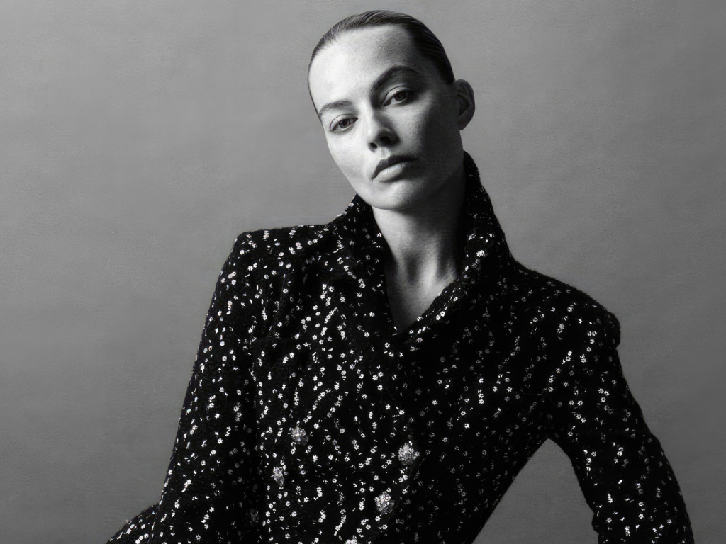 Грустная Марго Робби в блестящем пиджаке на сером фоне