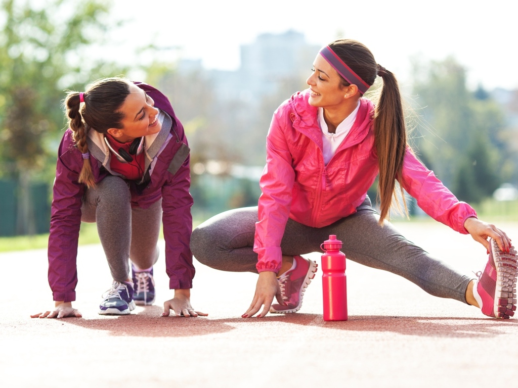 Две спортивные девушки делают растяжку 