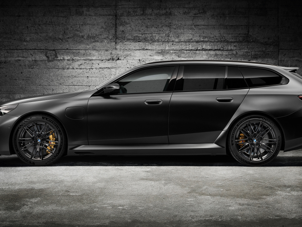 Вид сбоку на черный автомобиль BMW M5 Touring 2024 года