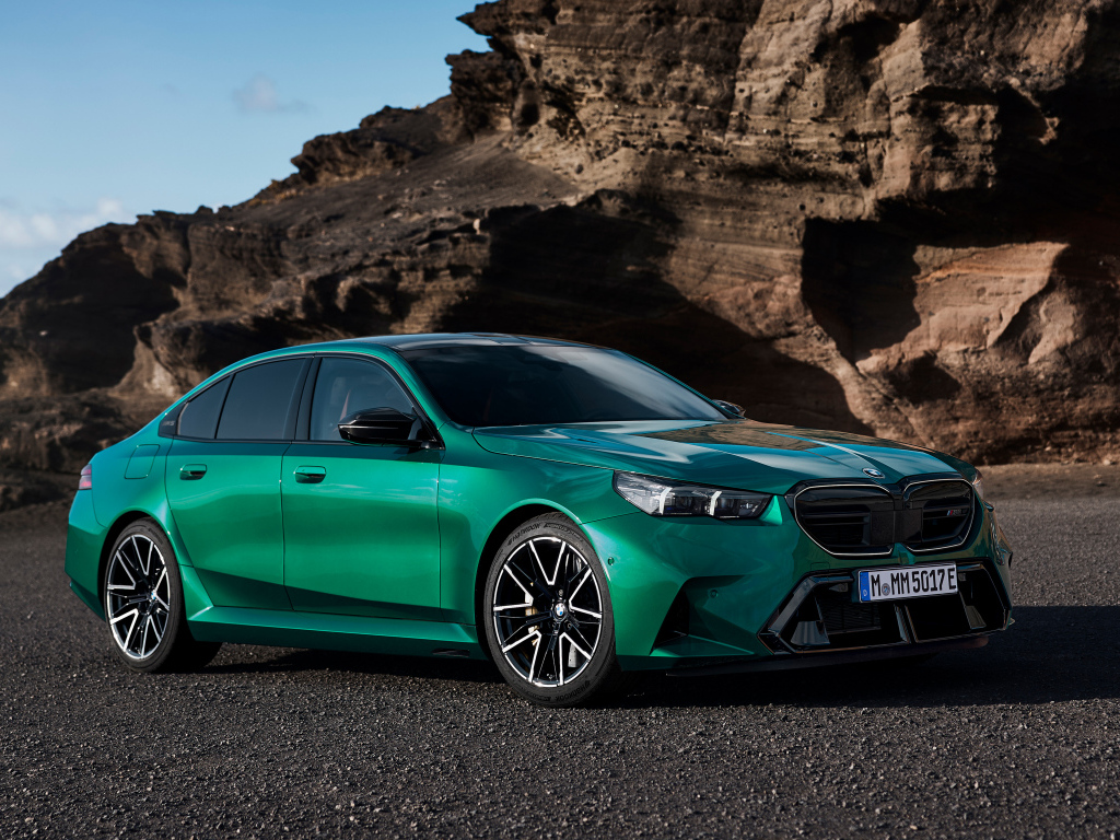 Зеленый автомобиль BMW M5 2024 года на фоне гор