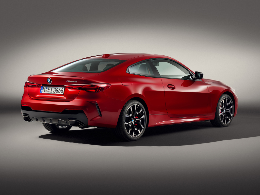 Красный автомобиль BMW M440i XDrive Coupé 2024 года на сером фоне