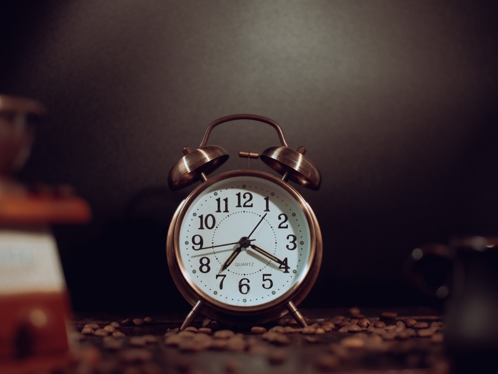 Будильник на столе с зернами кофе