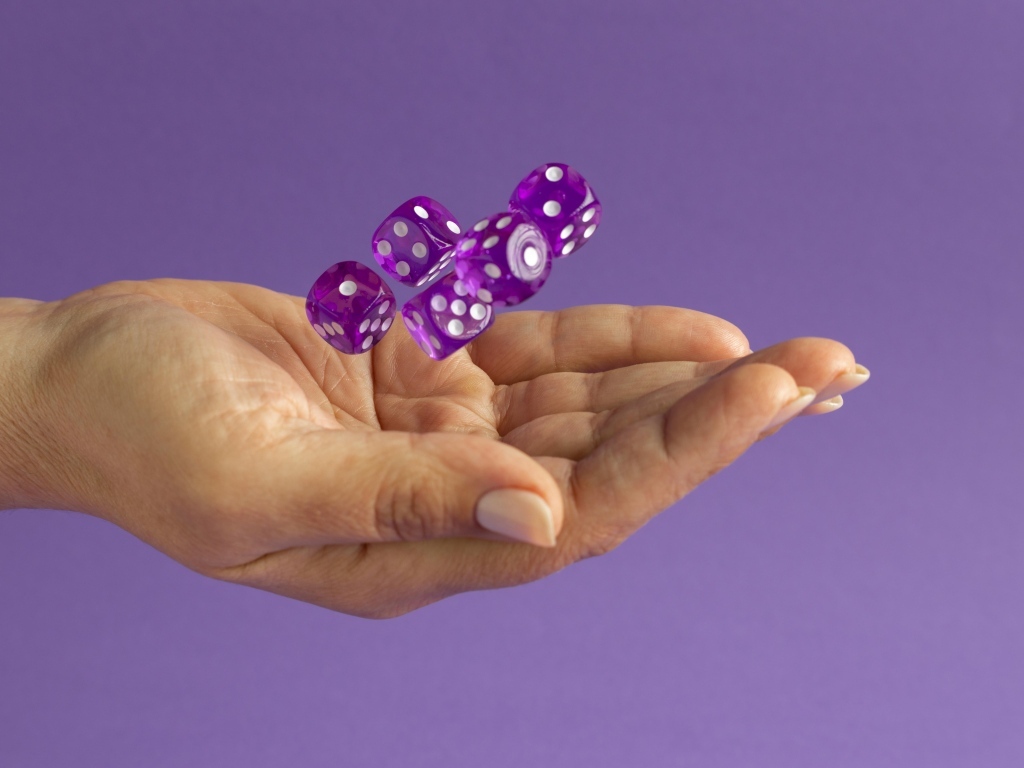 Игральные кости в ладони на сиреневом фоне