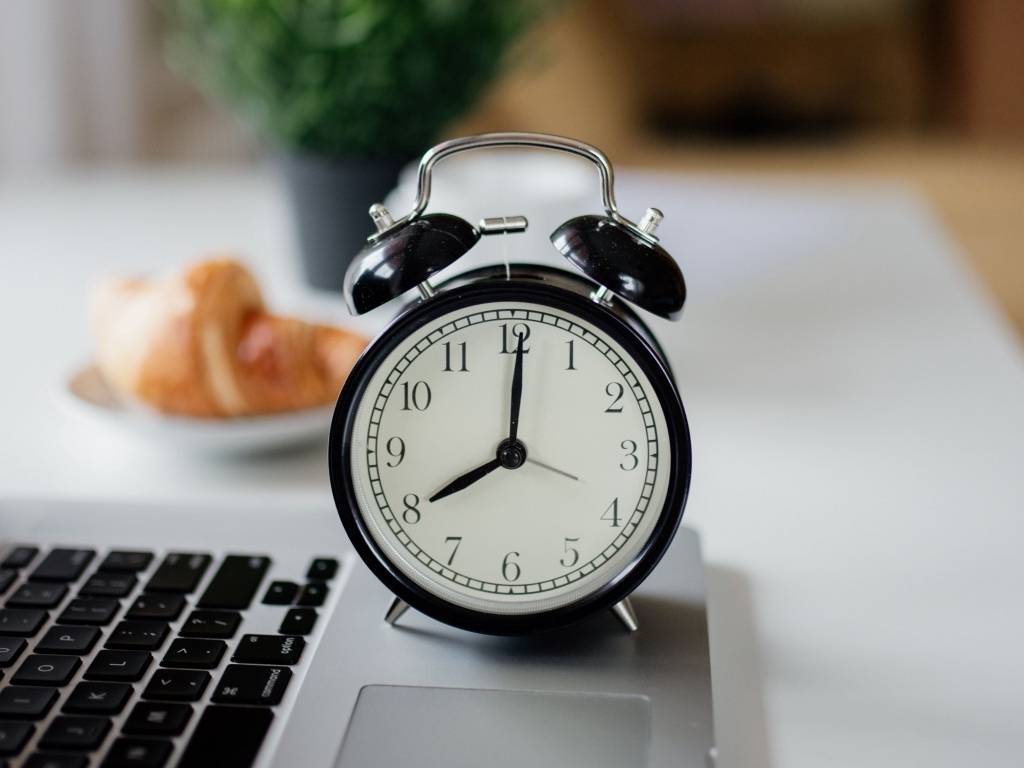 Большой черный будильник на столе у ноутбука