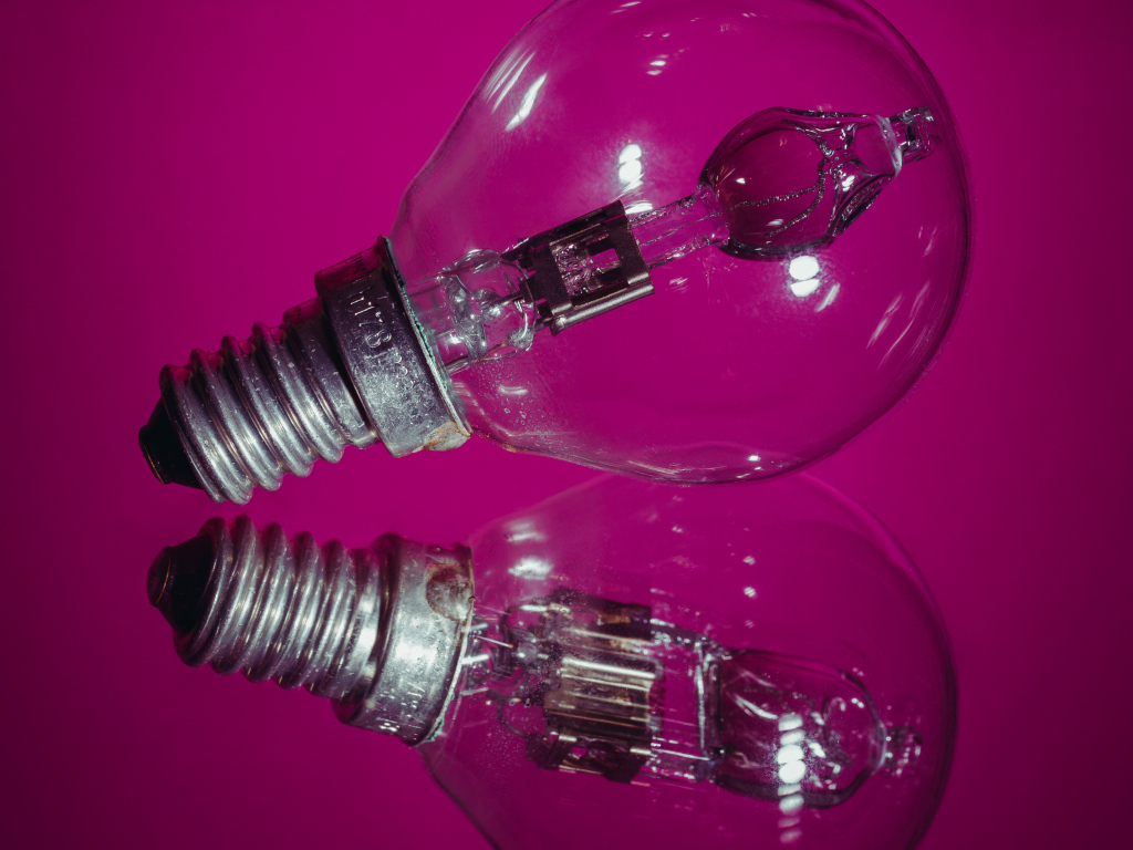 Лампочка отражается в поверхности на сиреневом фоне