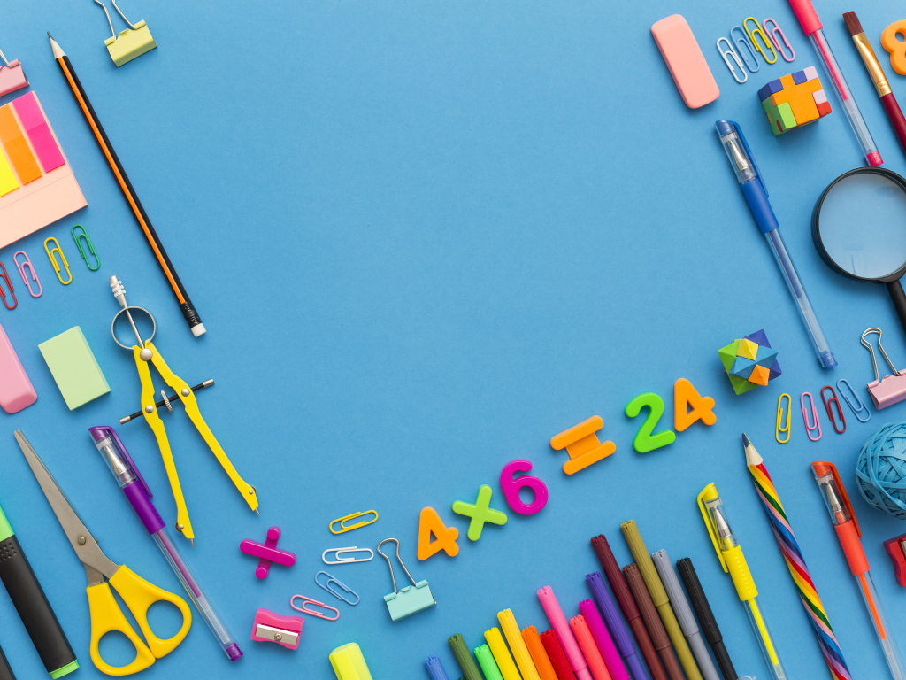 Много разных канцелярских предметов на голубом столе