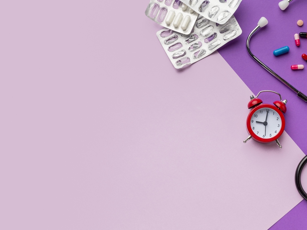 Таблетки, стетоскоп и будильник на сиреневом фоне
