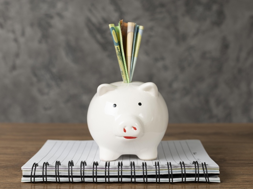 Свинья копилка с купюрами на столе с блокнотом