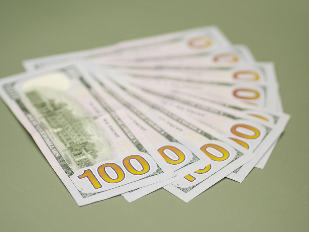 Пачка стодолларовых купюр на зеленом фоне