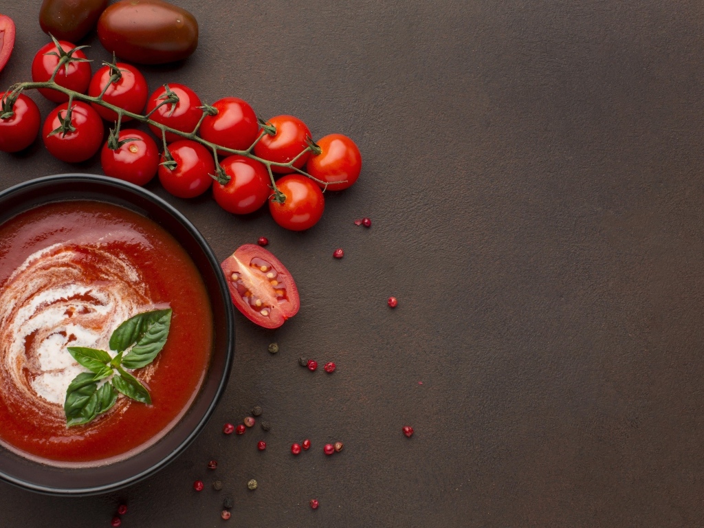 Кетчуп в тарелке на столе с помидорами