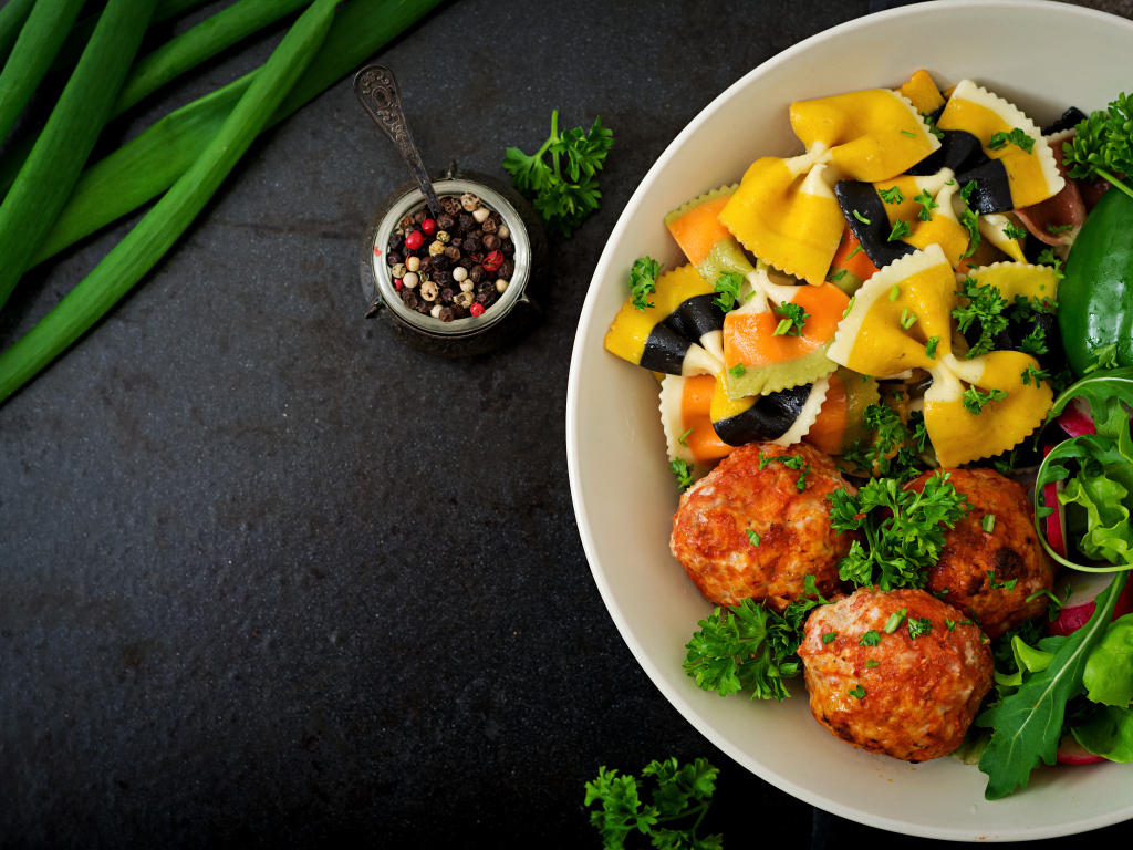 Паста с тефтелями и салатом в тарелке