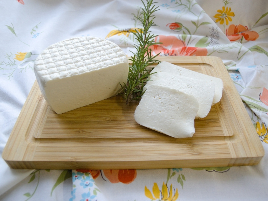 Кусок сыра с розмарином на разделочной доске