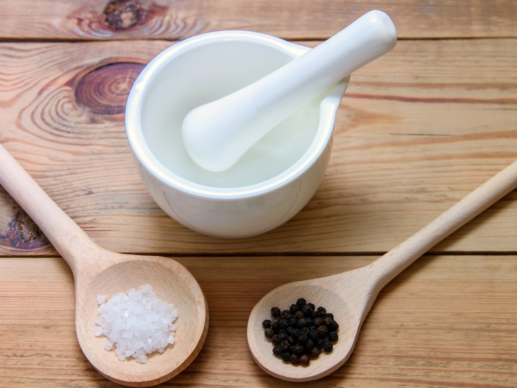 Соль с перцем на столе с деревянной ступкой