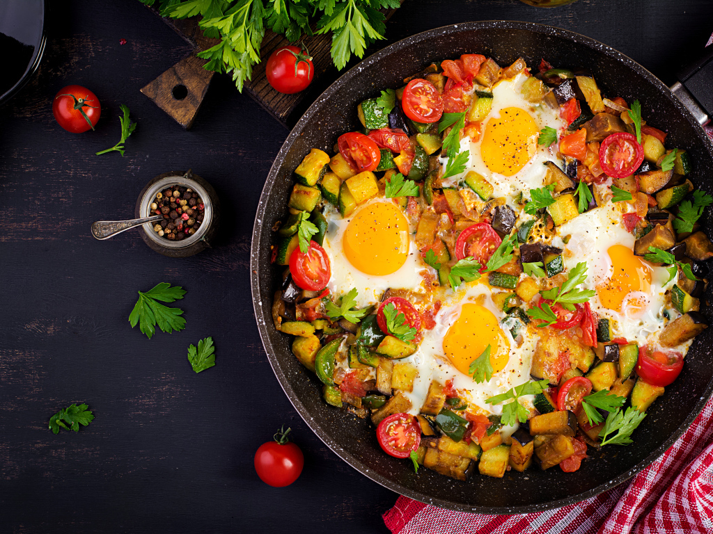 Яичница с овощами в сковороде на столе
